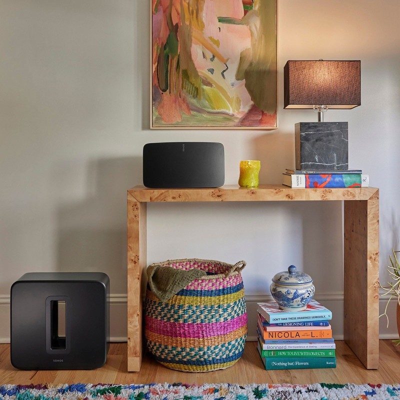 Sonos Sub 4 negro colocado junto a una estantería en un salón
