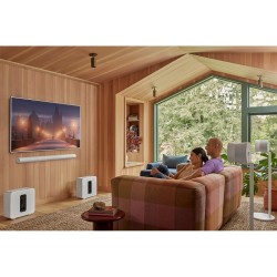 Sonos Sub 4 blanco junto al sofá en un salón revestido de madera