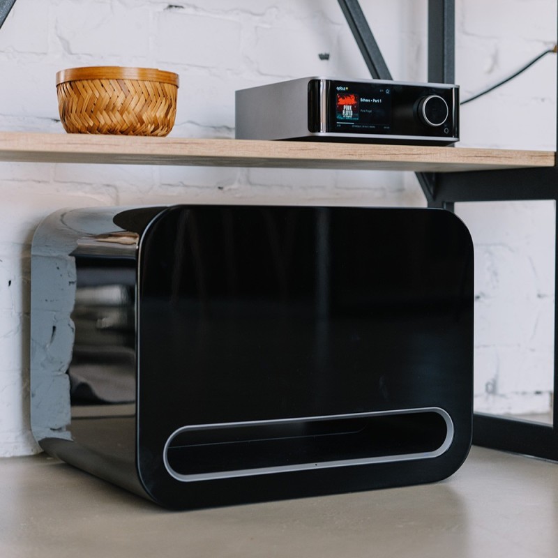 WiiM Sub Pro Subwoofer Activo negro — vista frontal en ambiente con amplificador