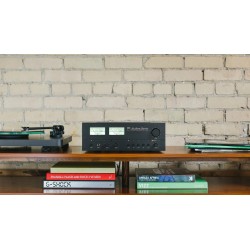 NAD C 3030S — sobre una estantería con libros junto a una pared de ladrillo