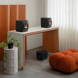 KEF KC62 Carbon Black — junto a un mueble con altavoces, ambiente