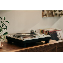 Cápsula Ortofon MC Cadenza en un tocadiscos, con discos de vinilo detrás