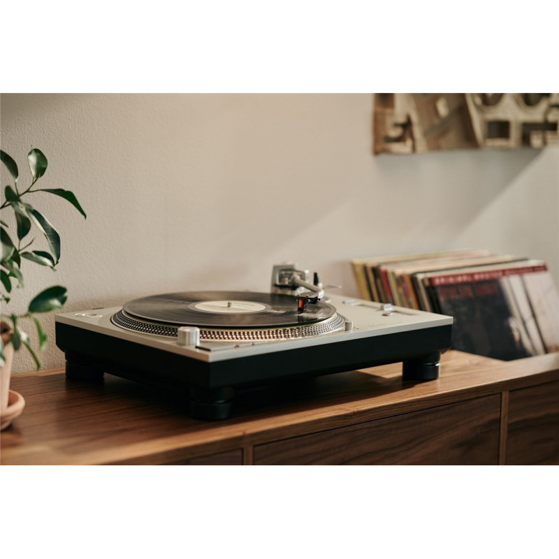 Cápsula Ortofon MC Cadenza en un tocadiscos, con discos de vinilo detrás
