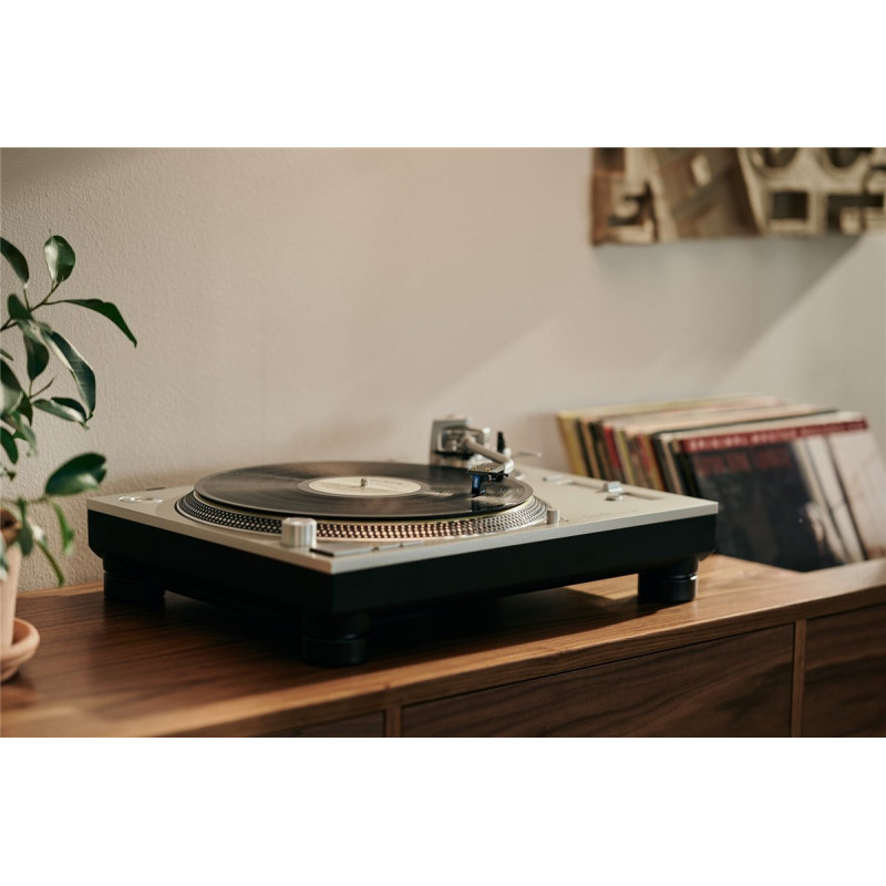 Cápsula Ortofon MC Cadenza en un tocadiscos, con discos de vinilo detrás