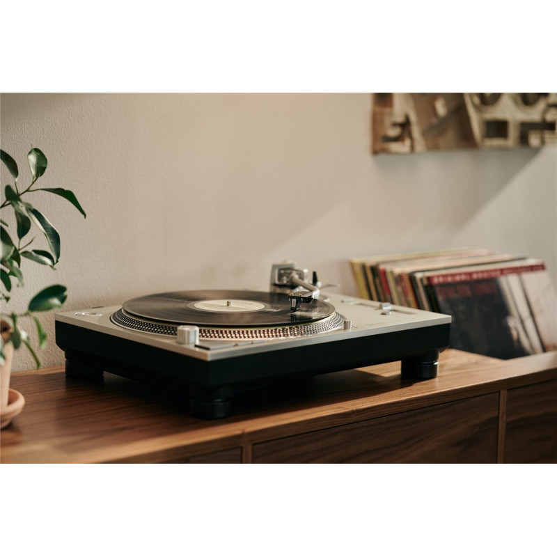 Cápsula Ortofon MC Cadenza en un tocadiscos, con discos de vinilo detrás
