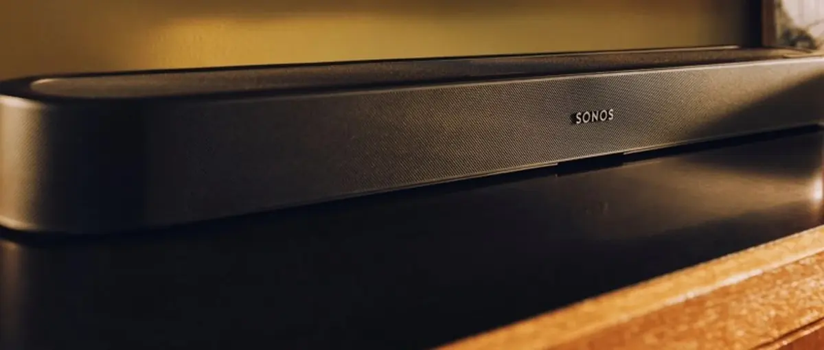 Sonos Beam Ultra negra instalada bajo un televisor OLED, sobre un mueble de madera